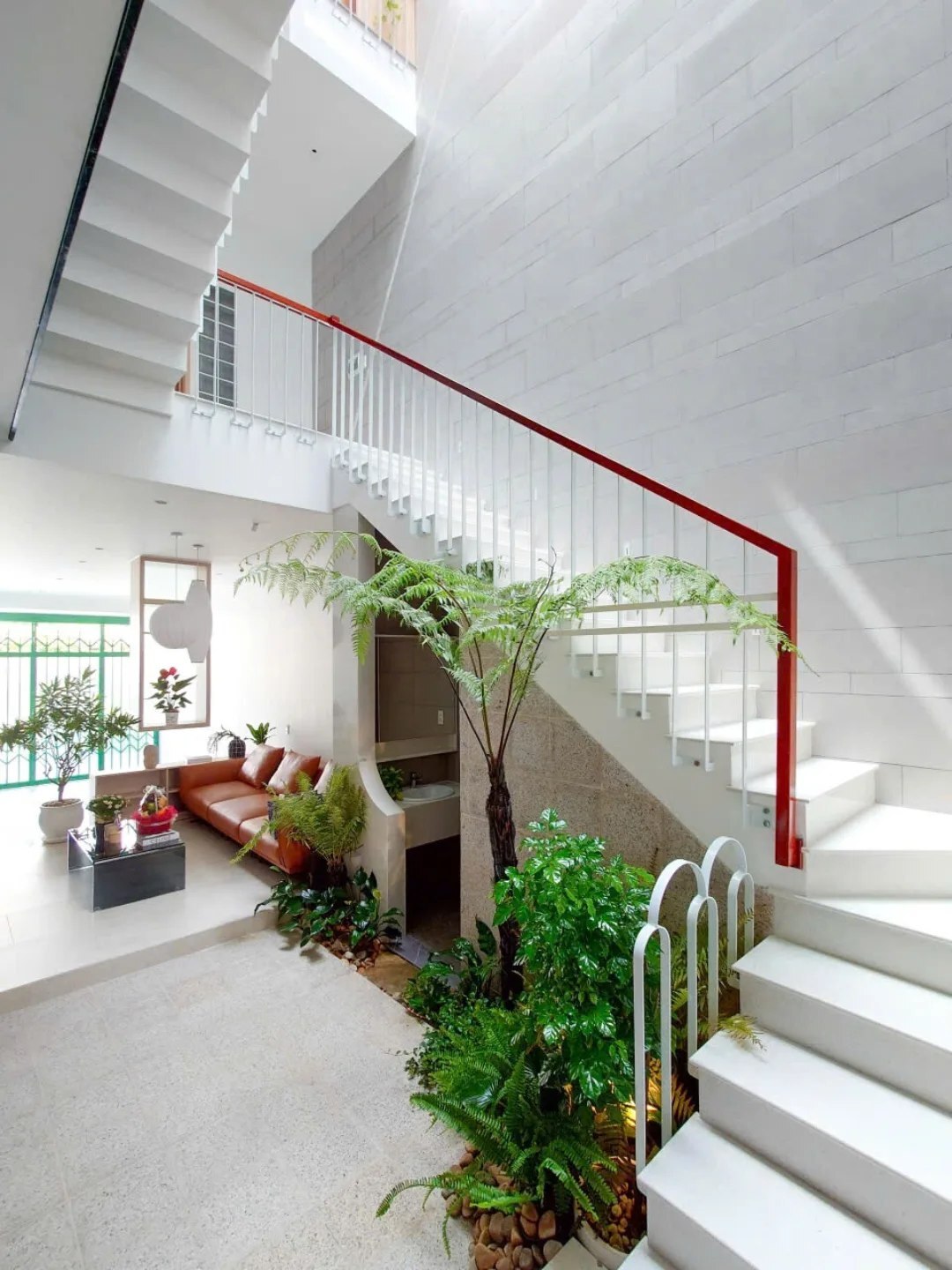 نمای خارجی و داخلی خانه چهار طبقه «شهر غربی» (Casa Cidade do Oeste) در ویتنام با مساحت ۹۰ متر مربع، که طراحی آن شامل نمای ساده، لایه‌های انبوه گیاهی برای حفظ حریم خصوصی، و فضاهای داخلی پلان باز با نورگیر مرکزی برای ایجاد محیطی آرام و روشن است.