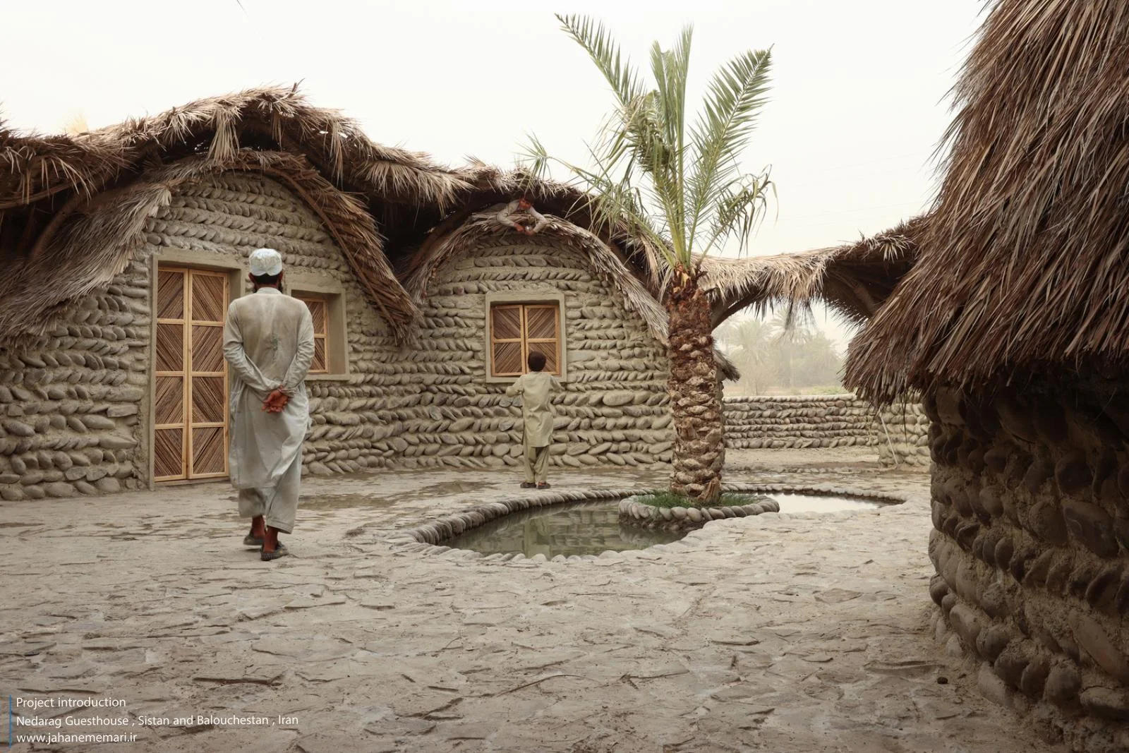 نمای خارجی و داخلی مهمانسرای ندارگ در روستای کهنانیکش، سیستان و بلوچستان، که ساختار نیمه‌باز، سقف چتری‌شکل با خرپاهای دست‌ساز و دیوارهای ضخیم گلی آن بر اساس بازتفسیر معماری بومی «کپر» و با هدف خنک‌سازی طبیعی و مشارکت جمعی اهالی طراحی و اجرا شده است.